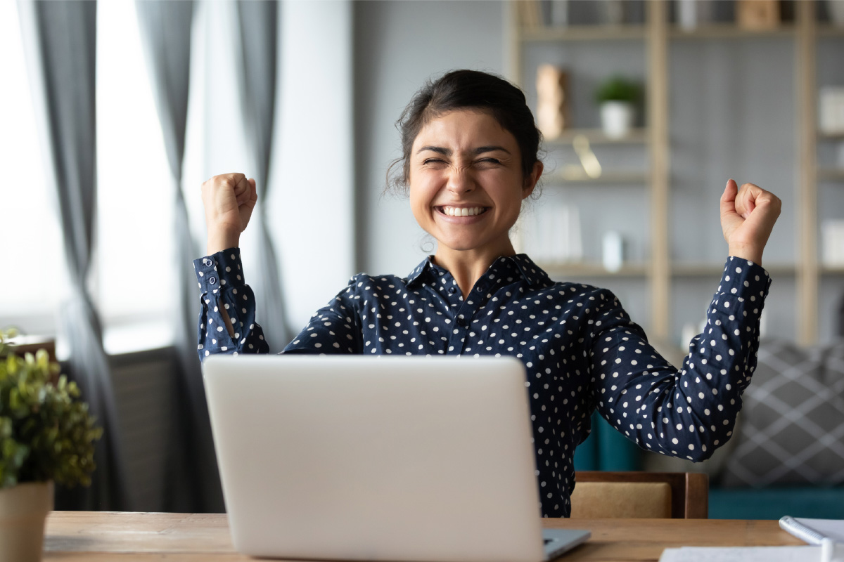 Smiling businesswoman celebrating a successful lead qualification outcome while working on her laptop, symbolizing effective lead qualification strategies.