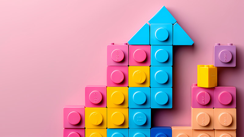 Lego blocks building upward, symbolizing the alignment and efficiency of RevOps by breaking down silos across revenue teams.