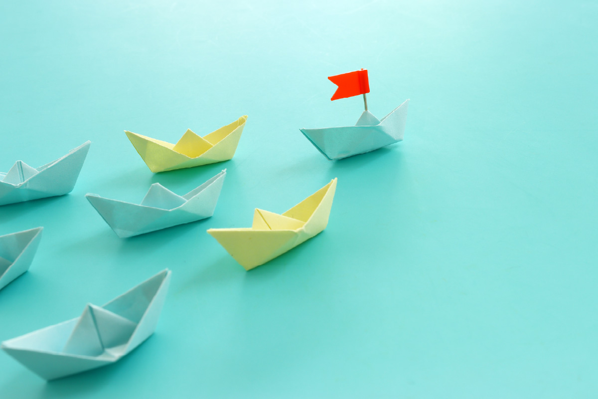 Origami paper boats symbolizing different Salesforce lead management software solutions, with one boat carrying a red flag to represent the top-ranked lead management tool.